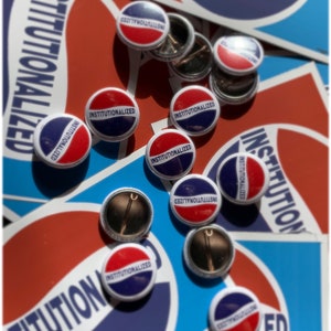 May include: A collection of round, red, white, and blue buttons with the text "INSTITUTIONALIZED" printed on them. The buttons are scattered on a blue and red background.