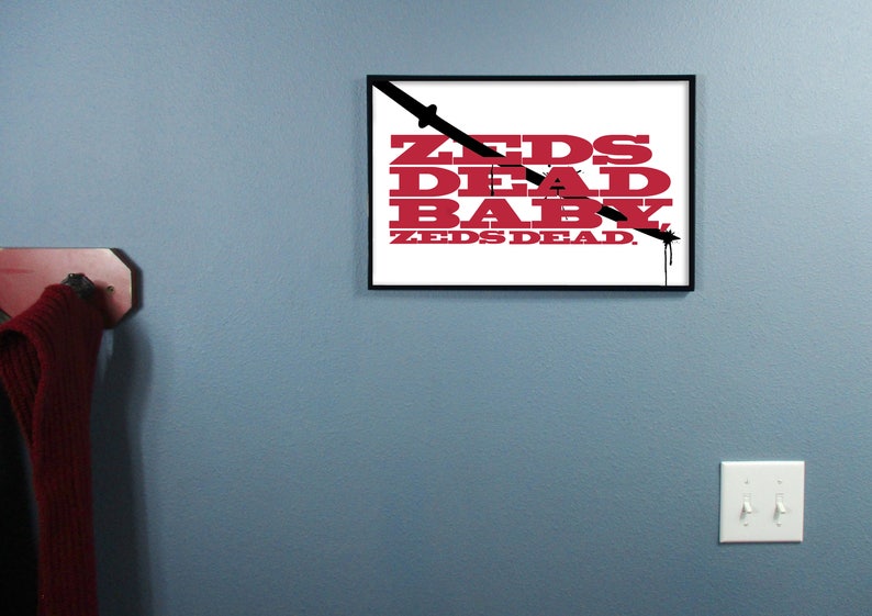 Puede incluir: Una impresi&oacute;n enmarcada en blanco y negro con el texto "ZEDS DEAD BABY ZEDS DEAD" en letras rojas. Una l&iacute;nea negra cruza el texto en diagonal.