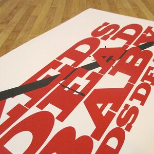 Puede incluir: Un p&oacute;ster blanco con texto rojo y negro que dice "ZOMBIES EAT BRAINS DEAD". El texto est&aacute; estilizado con una l&iacute;nea diagonal negra que lo atraviesa.
