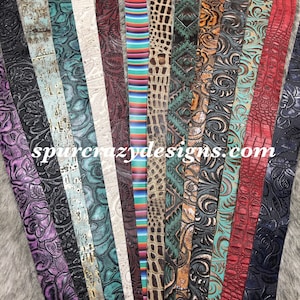 May include: A collection of 16 different leather straps with various embossed patterns and colors, including floral, geometric, and animal prints. The straps are arranged in a vertical row and are all approximately 1 inch wide. The text "spurcrazydesigns.com" is visible at the bottom of the image.