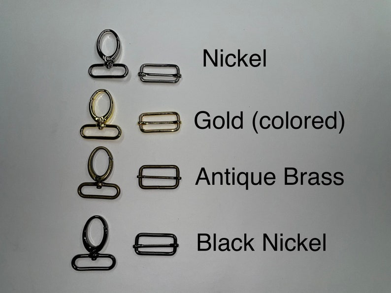 K&ouml;nnte beinhalten: Vier Sets aus Metallbeschl&auml;gen, jeweils bestehend aus einem drehbaren Karabinerhaken und einer rechteckigen Schiebeschnalle. Die Oberfl&auml;chen sind als Nickel, Gold (colored), Antique Brass und Black Nickel beschriftet und in Reihen angeordnet.