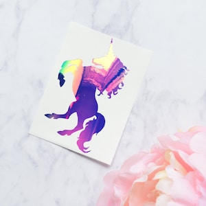 May include: A holographic unicorn silhouette sticker on a white background. The unicorn is facing right and has a rainbow iridescent finish.