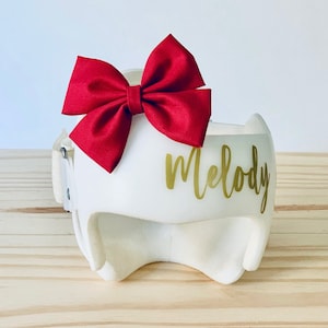 May include: White helmet with a red bow and the name "Melody" written in gold lettering.
