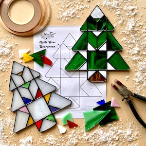 Könnte beinhalten: Ein Bleiglas-Set zum Herstellen eines Quilt-Stern-Evergreen-Baums. Das Set enthält eine Vorlage, Glasscheiben und Anweisungen. Die Glasscheiben sind in verschiedenen Farben, darunter Grün, Weiß und Rot.