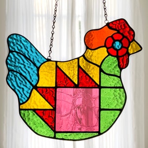 May include: A stained glass chicken window hanging with a patchwork design in shades of blue, yellow, red, green, and pink.