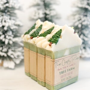 May include: Handmade soap bars with a tree farm design. The bars have a green base with white frosting and green tree accents. Each bar is wrapped with a brown paper label that reads "The Crafty Rose" and "Tree Farm".
