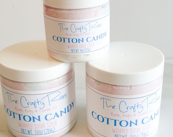 May include: Three jars of whipped sugar scrub with pink and white contents. The labels are white with blue text and say "The Crafty Roses Bath, Body & Candle Co. Cotton Candy Whipped Sugar Scrub" and list the net weight in ounces and grams.