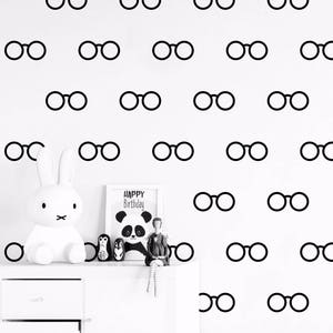 May include: A white wall with a black and white pattern of glasses. The glasses are in a repeating pattern and are all the same size. There is a white bunny rabbit and a birthday card with a panda bear on it in the bottom left corner of the image.
