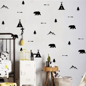 Puede incluir: Calcomanías de pared en blanco y negro con un tema de bosque con osos, montañas, árboles, tipis y flechas. Las calcomanías se muestran en una pared blanca en un entorno de guardería.
