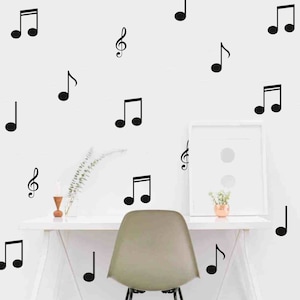 May include: Black and white music note wall decals on a white wall with a white desk and chair. The decals are in various sizes and shapes, including treble clefs and eighth notes.