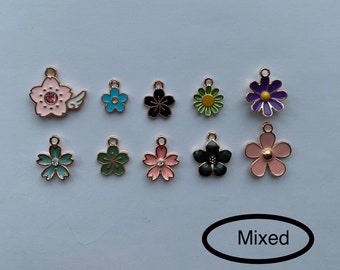 May include: Assortment of ten charm pendants featuring various flower designs. The charms are gold-toned with colorful enamel and rhinestones. The flowers include pink, blue, green, black, and purple.