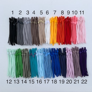 Puede incluir: Veintidos elásticos de diferentes colores con botones ajustables. Los elásticos están numerados del 1 al 22.