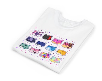 May include: A white t-shirt featuring a graphic print of twelve small, colorful, cartoon-style cats in various patterns and shades, including rainbow, pink, blue, and orange, surrounded by small purple and pink star-shaped sparkles.