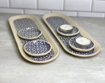 May include: Two white ceramic trays with blue and white geometric patterns. Each tray has two smaller bowls with the same pattern. One tray has two tealight candles in the bowls.