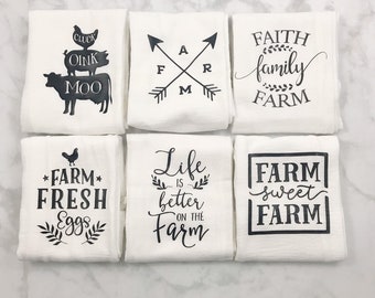 May include: Six white kitchen towels with black text and graphics. The towels feature farm-themed sayings such as "Farm Fresh Eggs", "Life is Better on the Farm", and "Faith Family Farm".
