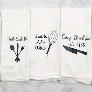 May include: Set of four white kitchen towels with black text and images. The towels feature the phrases "They See Me Rollin", "Just Eat It", "Watch Me Whip", "Chop It Like It's Hot", and "Shake It Like A Salt Shaker".
