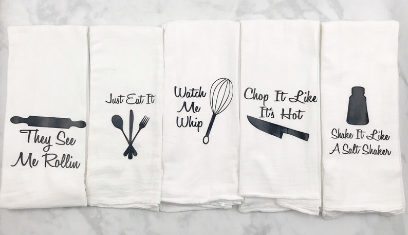 May include: Set of four white kitchen towels with black text and images. The towels feature the phrases "They See Me Rollin", "Just Eat It", "Watch Me Whip", "Chop It Like It's Hot", and "Shake It Like A Salt Shaker".