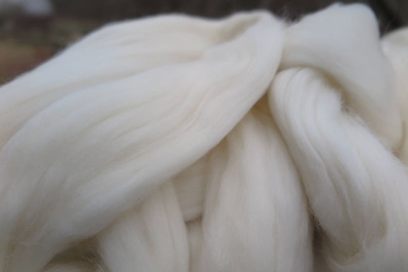 May include: A large, soft mass of unspun white wool roving with a fibrous, combed texture. The material consists of long, parallel strands of clean, off-white animal fiber arranged in a thick, continuous, and fluffy cloud-like formation.