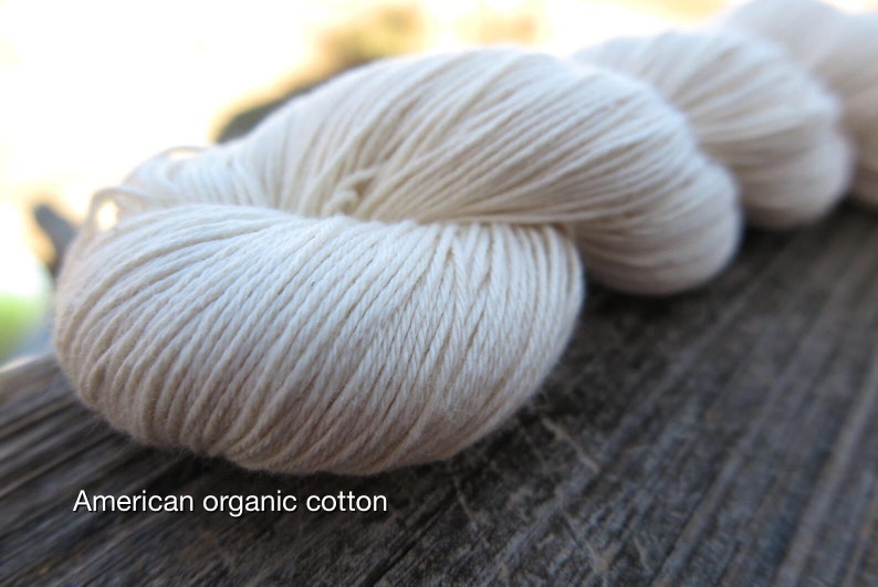 Peut inclure: Un &eacute;cheveau de fil blanc cass&eacute; avec une texture lisse et torsad&eacute;e. Le fil est &eacute;tiquet&eacute; comme American organic cotton. Les fibres sont &eacute;troitement fil&eacute;es en un brin continu, formant une forme arrondie et douce qui souligne la couleur cr&egrave;me.