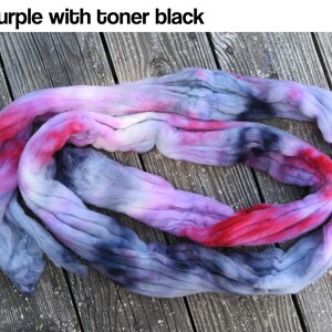 May include: A length of unspun wool roving featuring a variegated color palette of red, purple, and black tones. The text "Red purple with toner black" is printed at the top of the image, describing the fiber's blended color scheme.