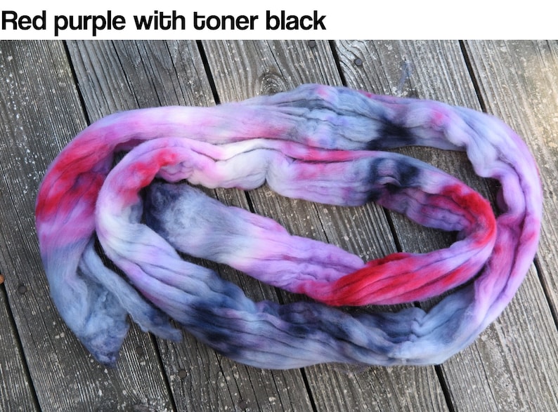 May include: A length of unspun wool roving featuring a variegated color palette of red, purple, and black tones. The text "Red purple with toner black" is printed at the top of the image, describing the fiber's blended color scheme.