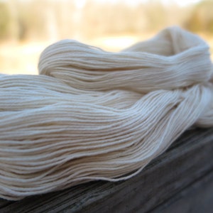 Peut inclure: Un &eacute;cheveau de fil blanc cass&eacute; compos&eacute; de plusieurs brins torsad&eacute;s. Le fil est enroul&eacute; en une longue boucle l&acirc;che, mettant en valeur la couleur cr&egrave;me naturelle et la finesse des brins uniformes qui composent toute la structure de cet &eacute;cheveau.