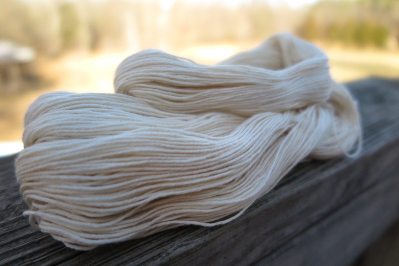 Peut inclure: Un &eacute;cheveau de fil blanc cass&eacute; compos&eacute; de plusieurs brins torsad&eacute;s. Le fil est enroul&eacute; en une longue boucle l&acirc;che, mettant en valeur la couleur cr&egrave;me naturelle et la finesse des brins uniformes qui composent toute la structure de cet &eacute;cheveau.