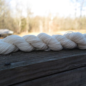 Peut inclure: Un &eacute;cheveau de fil torsad&eacute; de couleur blanc cass&eacute;. Le fil est compos&eacute; de multiples brins fins et &eacute;troitement fil&eacute;s qui cr&eacute;ent une texture lisse et uniforme sur toute la longueur du faisceau torsad&eacute;, lequel est dispos&eacute; horizontalement.