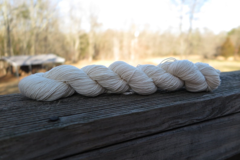 Peut inclure: Un &eacute;cheveau de fil torsad&eacute; de couleur blanc cass&eacute;. Le fil est compos&eacute; de multiples brins fins et &eacute;troitement fil&eacute;s qui cr&eacute;ent une texture lisse et uniforme sur toute la longueur du faisceau torsad&eacute;, lequel est dispos&eacute; horizontalement.