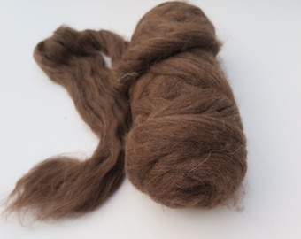 May include: A bundle of unspun brown wool roving, featuring a soft, fibrous texture. The wool is coiled into a dense, rounded mass on one side, with a long, loose strand extending outward, showcasing the natural, airy, and fluffy consistency.