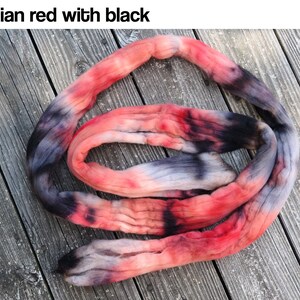 May include: A coiled length of hand-dyed yarn featuring a variegated color palette of vibrant red, soft pink, and deep black tones. The text "Egyptian red with black" is printed in the upper left corner of the image, describing the colorway.