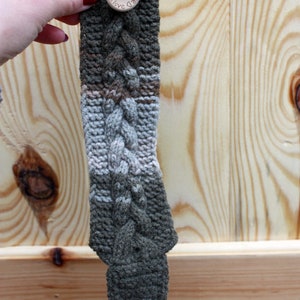 May include: A green, white, and brown knitted bracelet with a wooden button that says "Handmade with Love".