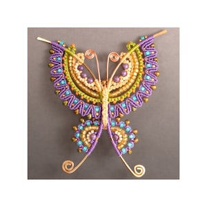 Könnte beinhalten: Ein Schmetterling aus lila, grünen und goldenen Perlen mit Kupferdrahtflügeln.