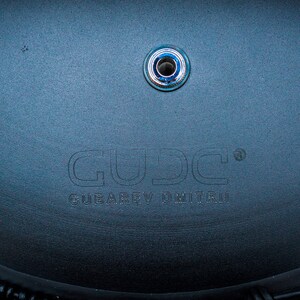May include: Close-up of a black bicycle seat with a silver metal screw and the text "GUD.C. GEAR & DRIVE" embossed on the surface.
