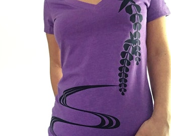 May include: Purple short-sleeved t-shirt with a black floral design and a black wavy line design.