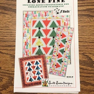 Könnte beinhalten: Ein Lone Pine Quiltmuster mit Anleitungen für passende Tischsets. Das Design zeigt grüne Bäume und rote Dreiecke auf weißem Hintergrund. Das Muster enthält den Text "X Blocks" und "Quilt Queen Designs."