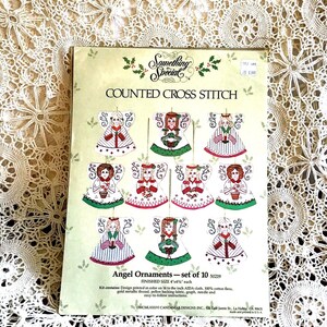 May include: A craft kit for counted cross stitch angel ornaments. The kit includes a set of ten angel designs, each measuring 4x4 inches. The packaging features the text "Something Special" and "COUNTED CROSS STITCH".