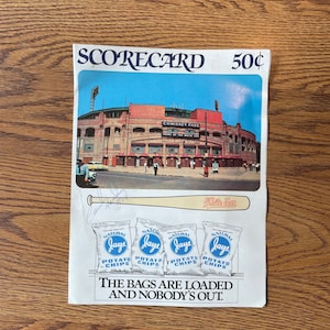 May include: A vintage scorecard for a baseball game at Comiskey Park, home of the White Sox. The scorecard features a photo of the stadium and a slogan: "The bags are loaded and nobody's out." It also features an advertisement for Jays Potato Chips.