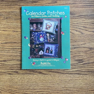 May include: A teal blue book with a white title "Calendar Patches for Pillows, Quilts, and Clothing" and a picture of a bookshelf with four pillows on it. The book is by Nancy J. Smith & Lynda S. Milligan and Passionate Quilts.