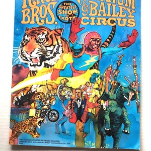 May include: A 1979 Ringling Bros. and Barnum & Bailey Circus souvenir program magazine featuring a blue background with a tiger, a superhero-like figure, an elephant, and performers. The text reads Ringling Bros. and Barnum & Bailey Circus.