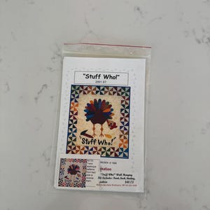 May include: A clear plastic bag containing a quilting pattern titled "Stuff Who!" featuring a colourful turkey design. The pattern includes instructions and materials for a wall hanging.