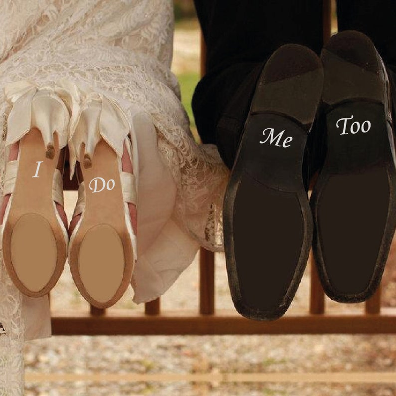 May include: A bride and groom's shoes with the words "I Do" and "Me Too" written on them.
