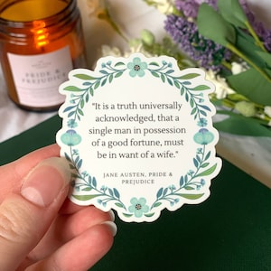 May include: A white sticker with a floral border and a quote from Jane Austen's Pride and Prejudice: "It is a truth universally acknowledged, that a single man in possession of a good fortune, must be in want of a wife."