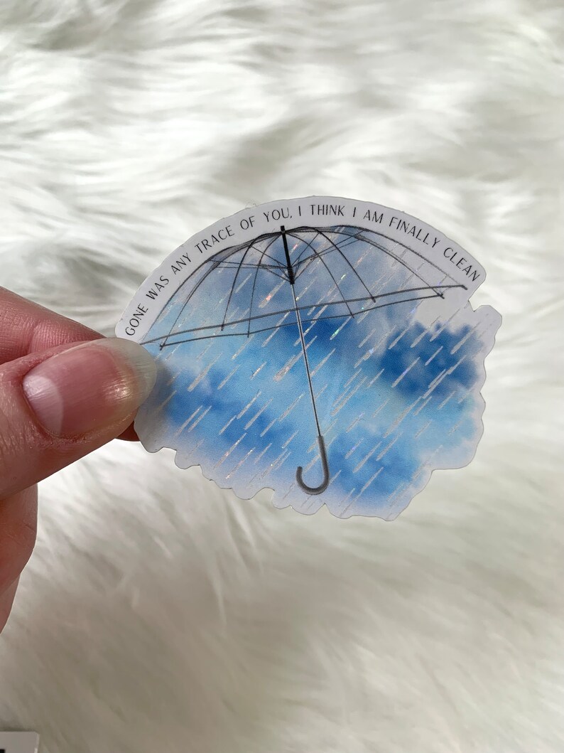 May include: A blue and white watercolour sticker with a black umbrella and the text "Gone was any trace of you, I think I am finally clean".
