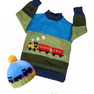 Könnte beinhalten: Ein blauer und grüner gestreifter Pullover für Kleinkinder mit einem roten und gelben Zugmotiv. Der Pullover ist doppelt gestrickt und hat eine passende Mütze mit einem gelben Bommel.