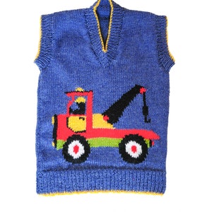 Pode incluir: Um colete azul de malha com uma borda amarela e um design de caminhão de reboque vermelho, amarelo e preto. O colete é para um peito de 61 a 81 cm. "Recovery/Breakdown Truck" e "Double Knitting" estão escritos abaixo da imagem. "designs by Linda Moorhouse" está escrito abaixo do texto.