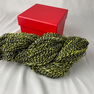 May include: A skein of black and neon yellow yarn, with a red box in the background.