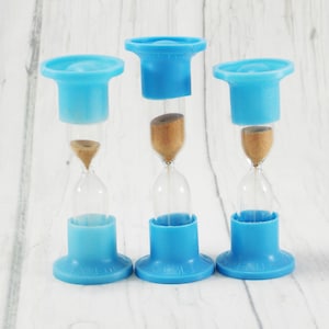 May include: Three blue hourglass sand timers with clear glass bulbs and brown sand. The top of each hourglass is a blue plastic cap.