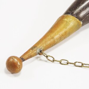 May include: A brown and black horn with a brass tip and a brass chain attached. The horn is about 12 inches long.