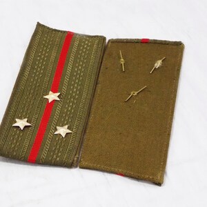 May include: Two green fabric patches with red stripes and gold stars. One patch has three gold stars and the other has three gold pins.
